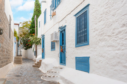Fototapeta A narrow residential alley with whitewashed walls and blue doors and trim in the seaside Greek village of Hydra, on the Saronic Island of Hydra, Greece.