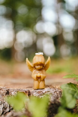 Candle made of natural arganic wax in the shape of a cute angel in nature. A candle on an old stump against the background of a forest. Hobby. Handmade present. Artistic photo of beekeeping products