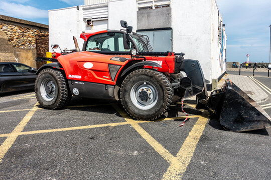 A red Manitou telehandler parked near a building on the pier in Howth, Dublin, Ireland.