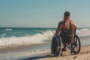Naklejka premium A Moment of Tranquility: Man in a Wheelchair Facing the Ocean on a Sunny Beach