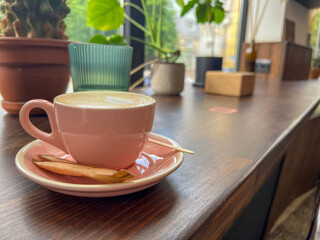 Cappuccino coffee cup at cafe table. Closeup of rosetta flower drawing in foam.
