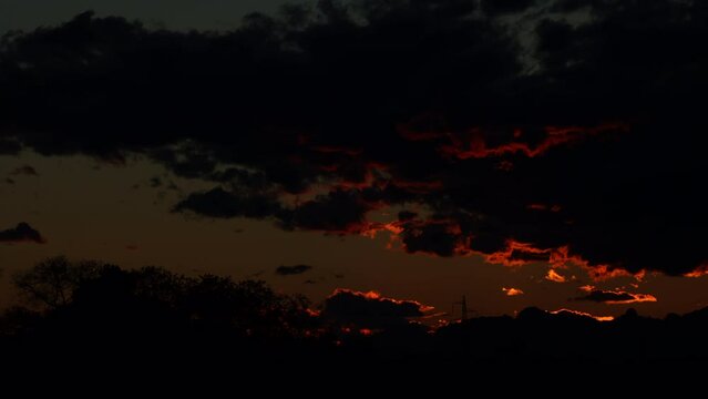 breve timelapse con inquadratura dettagliata del sole che tramonta dietro le nuvole e illumina il cielo di tante sfumature di arancione intenso