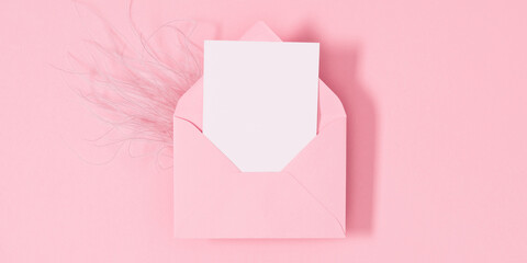 Open pink envelope with paper card on isolated pastel pink table background. Birthday, Wedding, Mother's Day, Valentine's day, Women's Day. Flat lay, top view, copy space