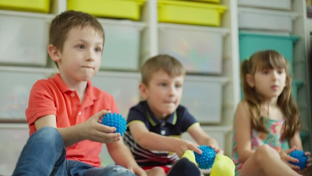 Children exercise between lessons using a massage ball. They run it over the body stimulating nerve endings and just have fun. High quality 4k footage