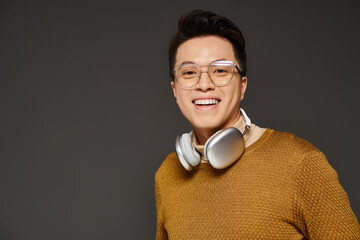 A fashionable young man dressed in a sweater, actively listening to music through headphones.