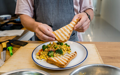 Chef at the kitchen preparing tofu scramble with vegetables