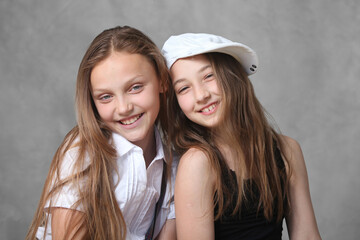 portrait of two cheerful preteen girls on grey background