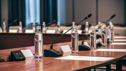 an empty conference panel table with bottles of water and microphones, press conference event setup