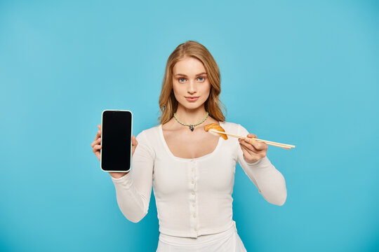 A stylish woman with blonde hair holding a chopstick and cell phone at the same time. - Powered by Adobe