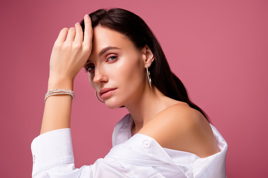 Photo of girl wear white shirt touch hand face with diamond bracelet isolated pink color background