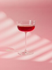 A sleek and elegant image of a cocktail glass filled with red liquid against a vibrant pink background. This modern composition is perfect for themes of elegance, style, and sophisticated beverages.