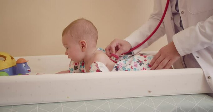 Experienced pediatric specialist examining baby's breathing using stethoscope.