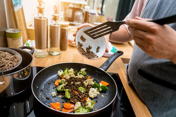 Chef at the kitchen preparing japanese buckwheat pasta with lentils