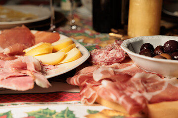 piatti con antipasti a base di vari tipi di salumi, formaggi e olive nere su un tavolo decorato in...