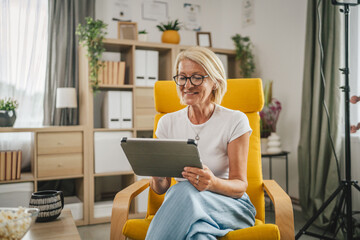 Mature senior woman sit at home and use tablet
