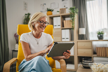 Mature senior woman sit at home and use tablet