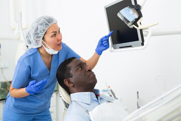 Obraz premium Doctor dentist shows patient an x-ray on computer
