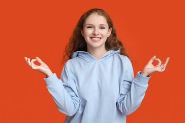 Portrait of relaxed young woman meditating on red background