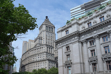 Naklejka premium Old office buildings with ornate stone carvings in lower Manhattan near Battery Park, with the former Custom House, now a museum