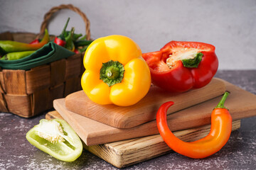 Wooden board with different fresh peppers on dark table