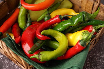 Basket with fresh chili peppers on dark table, closeup