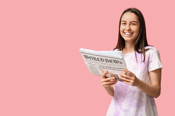 Beautiful young woman with newspaper on pink background