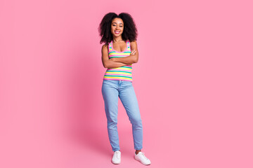 Full size photo of adorable positive woman dressed knit tank denim trousers holding hands crossed isolated on pink color background