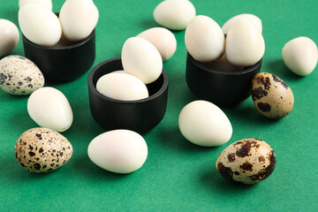 Bowls with fresh boiled quail eggs on green background