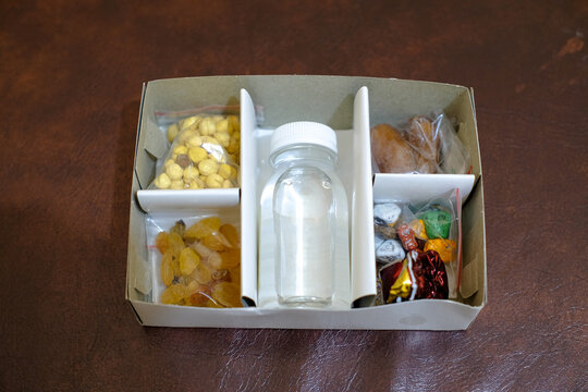 Umrah or Hajj souvenirs include zam zam water, dates, raisins, almonds, fig jam, in the box with brown background, stock photo.