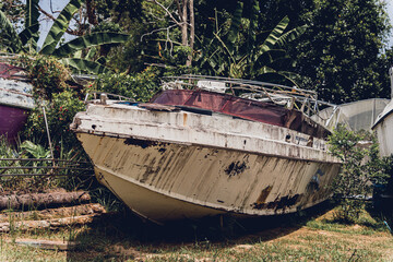 Old and rusty motor boats on a landfill surrounded by tropical forest