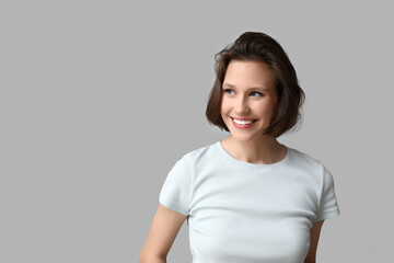 Beautiful young happy woman with bob hairstyle on grey background