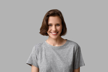 Beautiful young happy woman with bob hairstyle on grey background