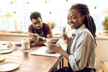 Two people sitting at the table and working with ceramic products