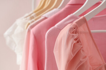Rack with hanging clothes near pink wall