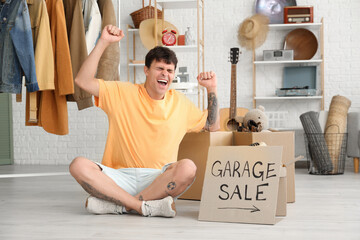 Happy young man with boxes in room of unwanted stuff. Garage Sale