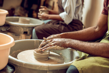 Close up of hands molding a shape of a product on a pottery wheel