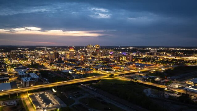 Hyperlapse of Birmingham, USA ,bright lights illuminate skyline at dusk, revealing prominent buildings and heavy traffic on the streets. View from above reveals the city road network and urban sprawl
