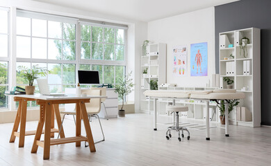 Interior of medical office with workplaces, massage couch and shelf units
