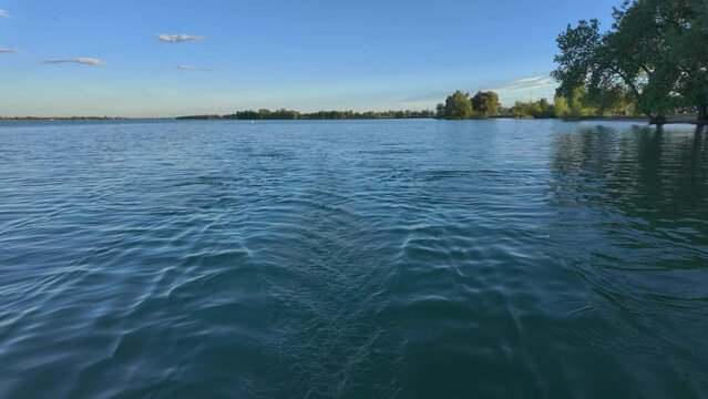 Lake view and wake behind a stern of recreational rowing shell, rower POV perspective, springtime on Boyd Lake in Colorado