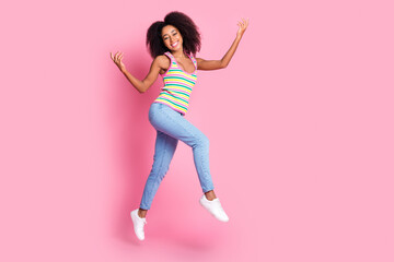 Full size photo of adorable pretty woman dressed knit tank jeans jumping flying raising palms up isolated on pink color background