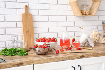 Bowl with tasty strawberries and juice on counter in kitchen