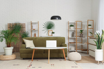 Interior of living room with green sofa, plants and folding screen