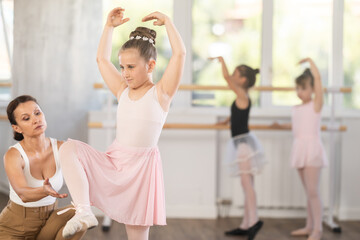 At ballet lesson, mentor corrects girls arm and leg, teaches correct dynamics and execution of...