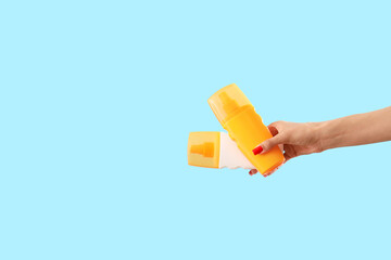 Female hand with sunscreen creams on blue background