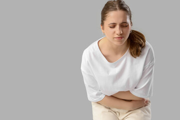 Young woman suffering from menstrual pain on light background