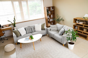 Interior of living room with grey sofas, table and plants
