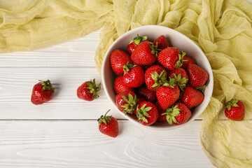 Bowl with sweet fresh strawberries on white wooden background