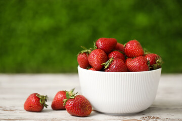 Bowl with sweet fresh strawberries on white wooden table outdoors