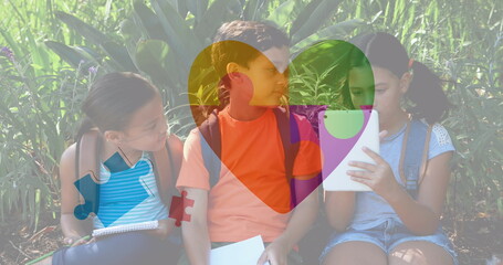 Image of colourful puzzle pieces and heart over kids friends using electronic devices