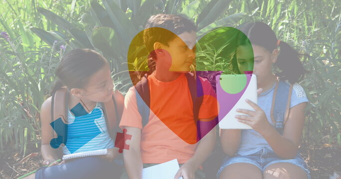 Image of colourful puzzle pieces and heart over kids friends using electronic devices